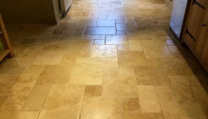 Worn travertine floor with dull patches and ingrained soil before restoration