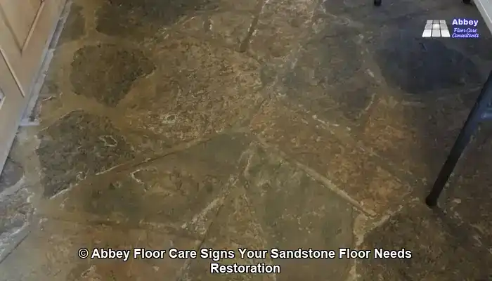 Uneven-looking sandstone floor with patchy dull areas, typical of worn protection and ingrained soil in domestic homes
