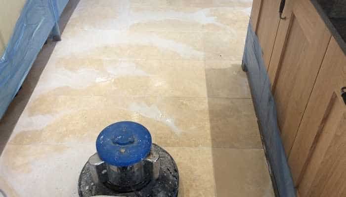 Rotary machine scrubbing a travertine floor during deep cleaning