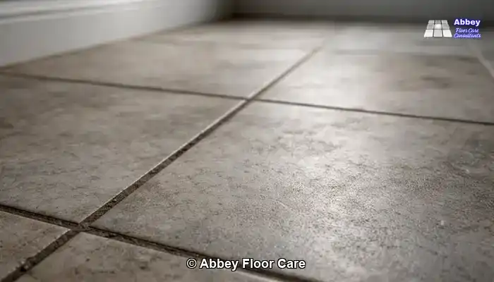 Close detail of textured porcelain tiles with surface haze and dark grout lines.