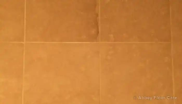 Close-up of a marble shower wall surface showing uneven light reflection from subtle etching