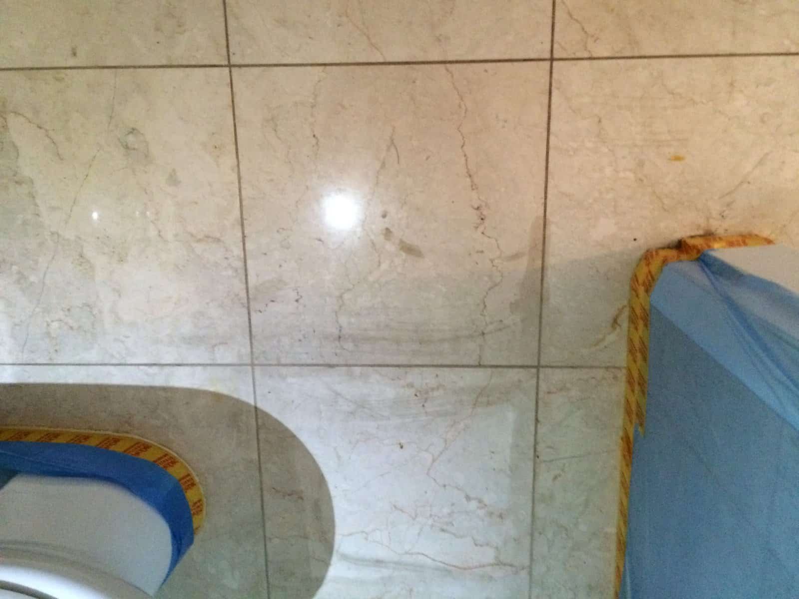 Grout and adjacent stone showing uneven colour and surface dullness after repeated cleaning