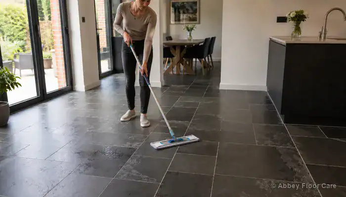 Mopping textured slate tiles with a damp microfiber mop and pH-neutral stone cleaner