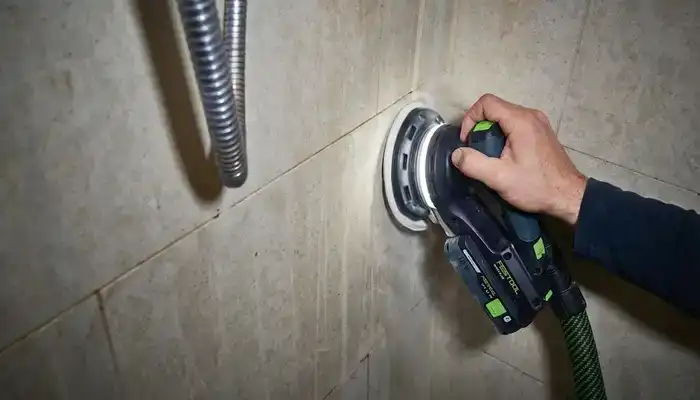 Hand honing being carried out on limestone shower surface