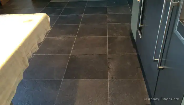 Textured porcelain tiles with grey residue trapped in recesses and grout lines