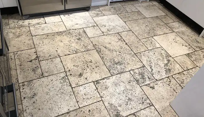 Travertine floor with darkened patches, worn finish and uneven surface tone