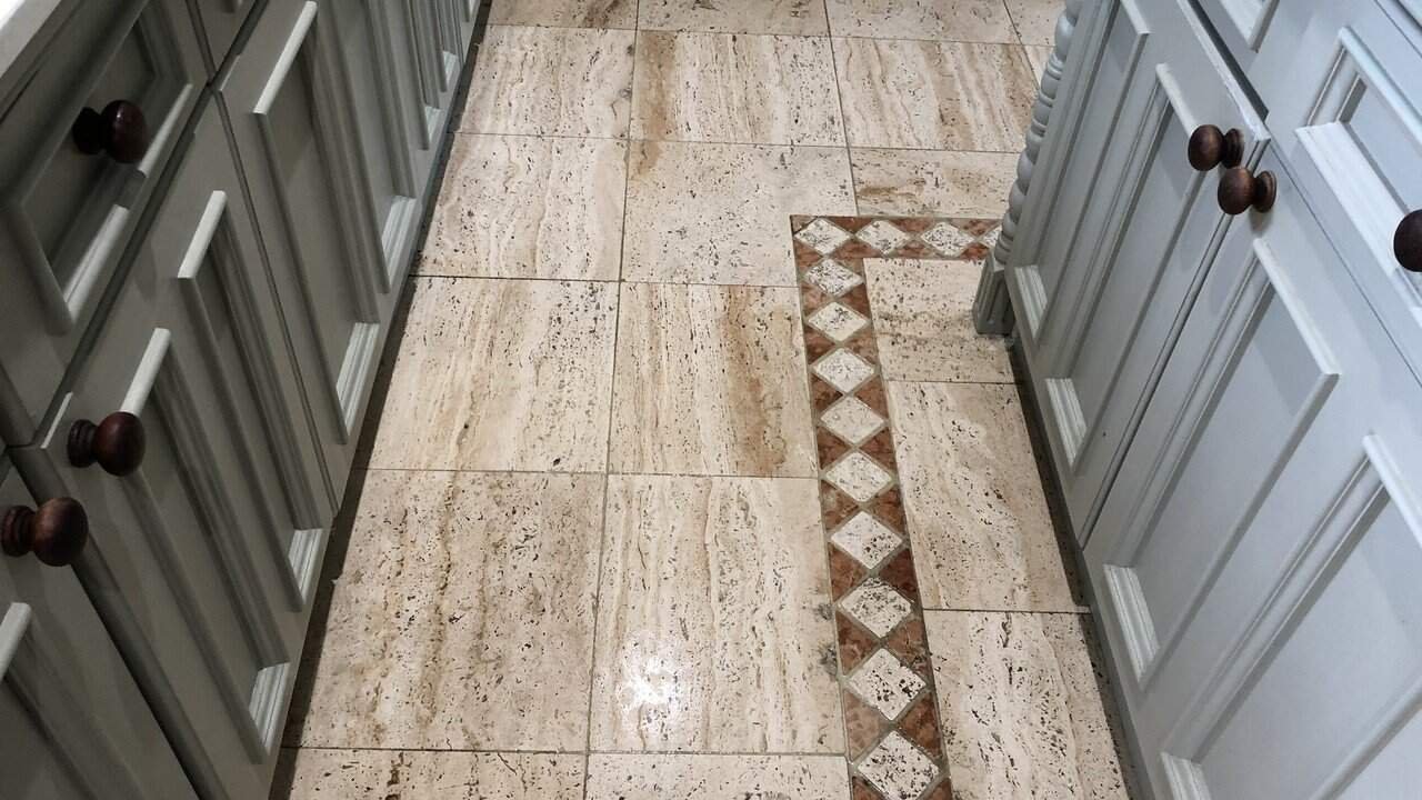 Worn travertine kitchen floor with dull traffic areas and natural colour variation