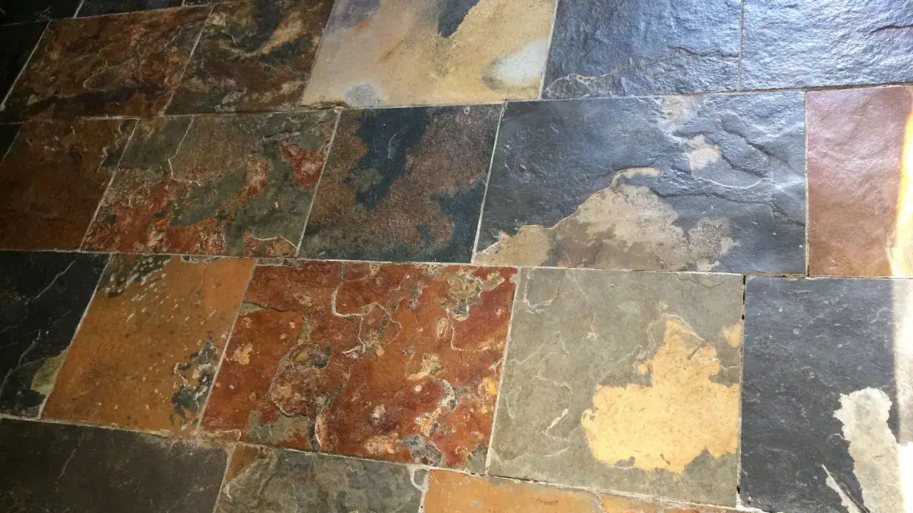 Slate floor surface showing flakes, grit and peeling patches